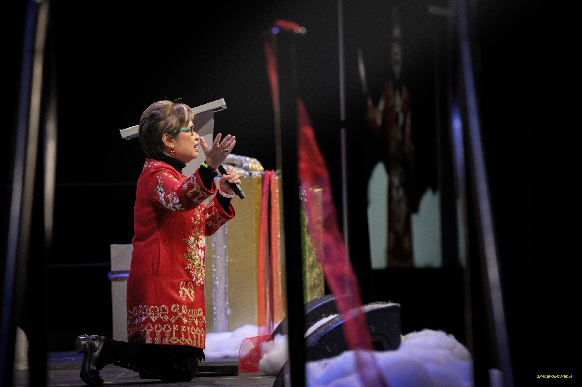 Susie kneeling in prayer on stage at ONEDAY 2020
